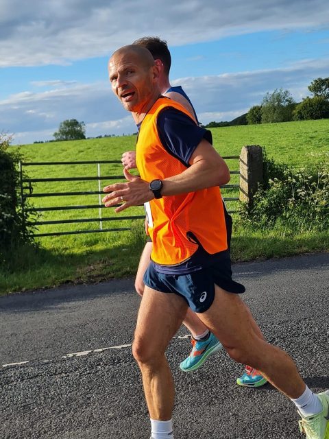 Andy running in orange vest and blue shorts 