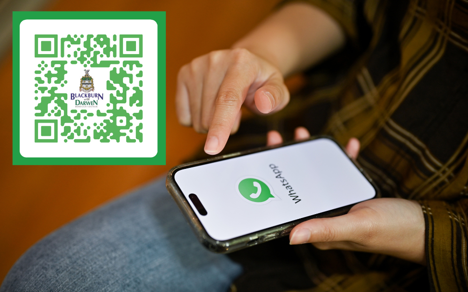 An image of a phone with WhatsApp open and a QR code in the top left hand corner