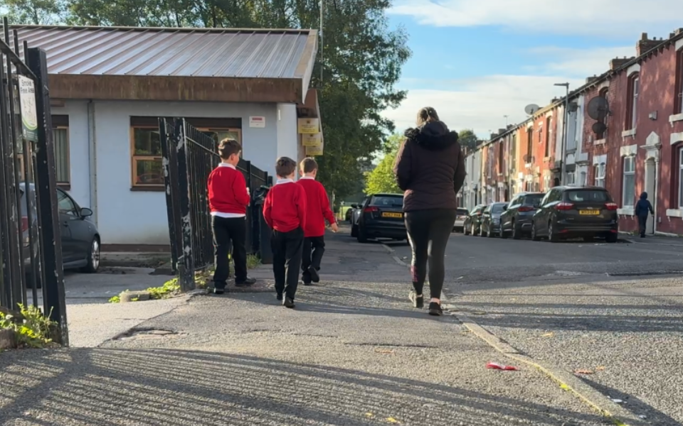 Three children walking with a parent to school.